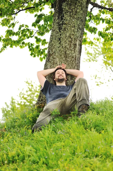 Szczęśliwy młody mężczyzna odpoczynek pod drzewem — Zdjęcie stockowe