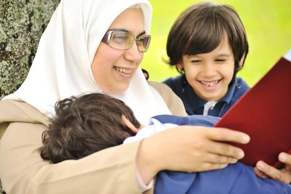 母亲穆斯林和她的儿子在自然，一起阅读 — 图库照片