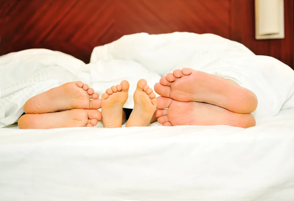 Família feliz na cama, seis pés — Fotografia de Stock