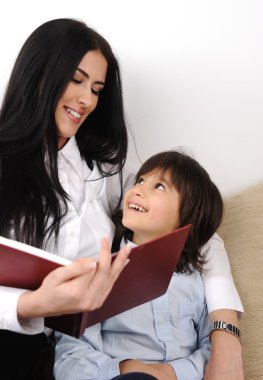 Mother and son reading book on the sofa clipart