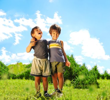 Two brother huging each other outdoor, smiling and laughing clipart