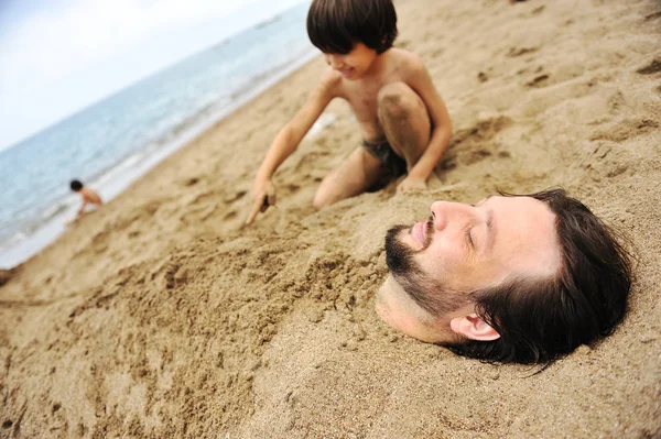 Playing with sand and digging the father in — Stock Photo, Image