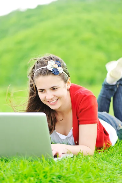一个微笑的小女孩与笔记本电脑进行户外 — 图库照片