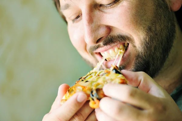 Młody człowiek jedzenie pizzy — Zdjęcie stockowe