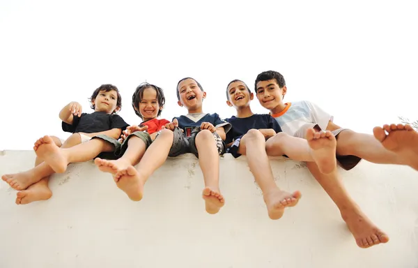 Niños sentados en la pared, niños felices riendo —  Fotos de Stock