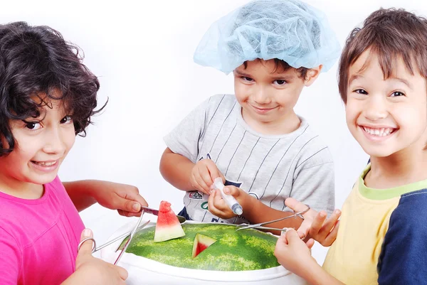 Kinder spielen um die Wassermelone wie im Operationssaal — Stockfoto