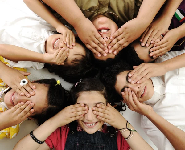Grup mutlu çocuklar yalan söylüyor ve gözleri eller tarafından kapatma — Stok fotoğraf