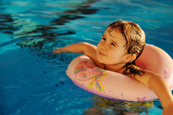 Kleines süßes Mädchen im blauen Wasser des Swimmingpools, Sommerzeit für — Stockfoto