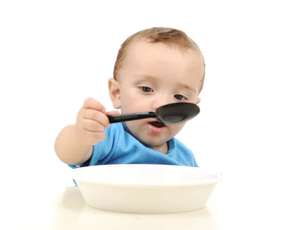 Niedliche entzückende einjährige Baby mit grünen Augen essen auf Tisch, Löffel und — Stockfoto