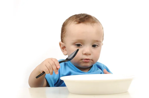 テーブルの上を食べる緑色の目で赤ちゃんのかわいいの愛らしい 1 歳、スプーンと — ストック写真