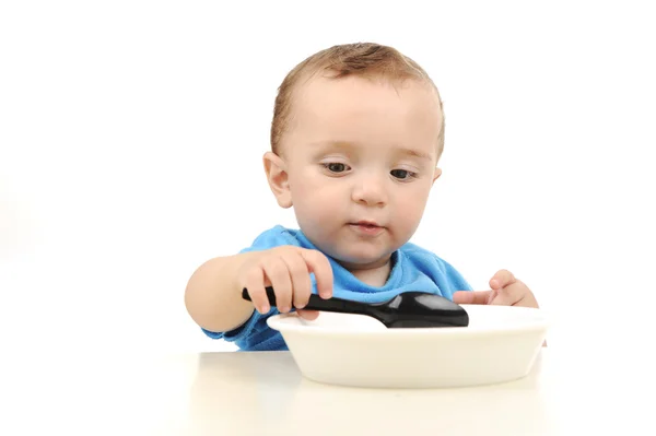 Roztomilý rozkošný jeden rok staré baby se zelenýma očima, jídlo na stole, lžíce a — Stock fotografie