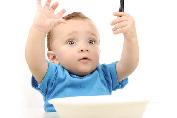 Cute adorable one year old baby with green eyes eating on table, spoon and — Stock Photo, Image
