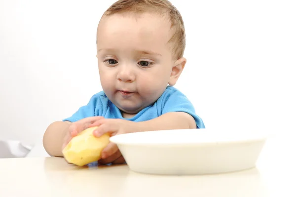 Cute adorable one year old baby with green eyes eating on table, spoon and — Stock Photo, Image