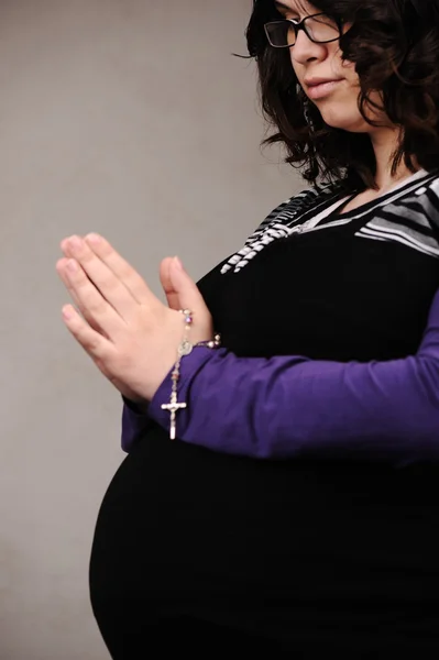 Schwangere betet mit Rosenkranz in der Hand — Stockfoto