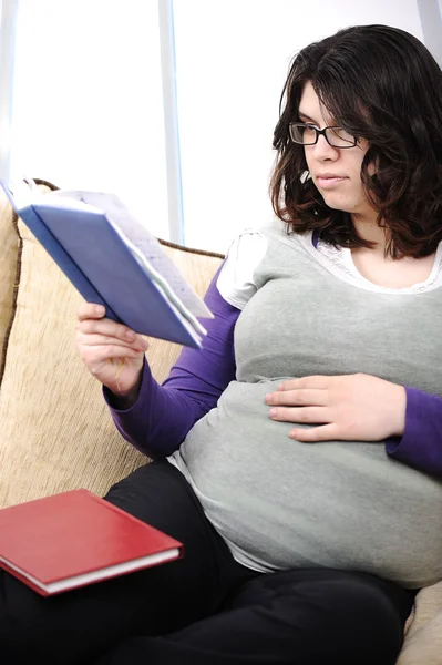 9 months pregnant woman sitting on sofa and reading book — Stock Photo, Image