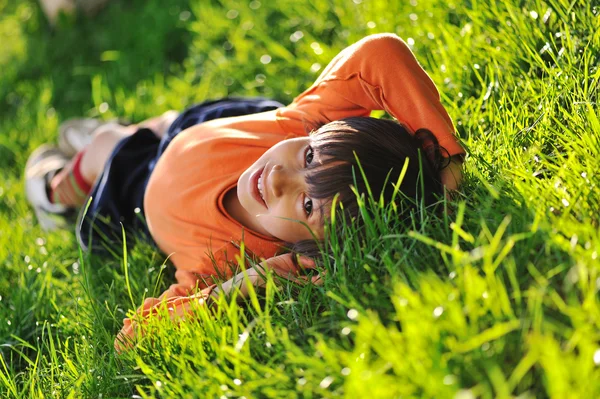 Happy boy laying on beautiful morning green grass — Stock Photo, Image
