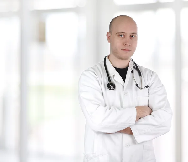 Leende säker läkare står med händerna korsade isolerade på vit baksida Stockbild