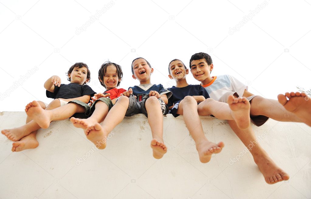 Children sitting on wall, happy boys laughing