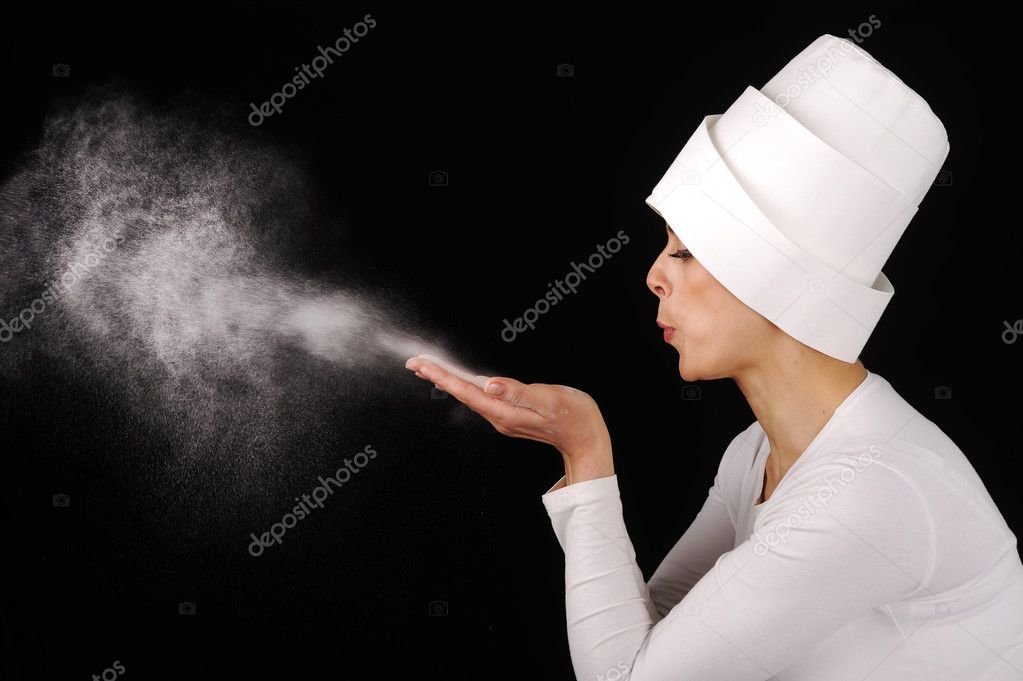 Beautiful woman blowing white powder on black background — Stock Photo