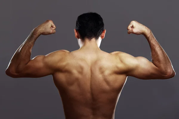 Young muscular guy over gray background