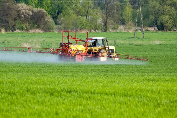 Tractor spraying green field — Stock Photo, Image
