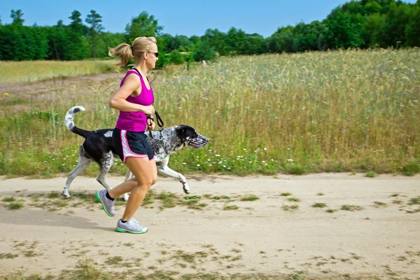 Mujer corriendo y paseando a un perro — Foto de Stock