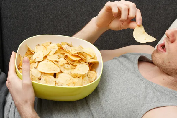 Människan äter chips — Stockfoto