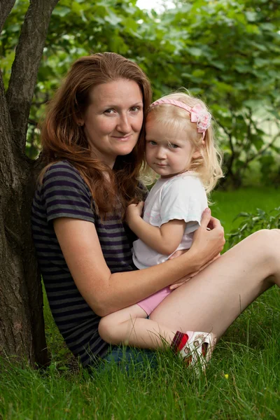 庭で草の上の娘を持つ母 — ストック写真