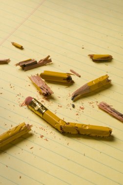 Broken pencil fragments on yellow paper clipart