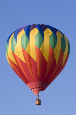 Colorful hot-air balloon against blue sky clipart