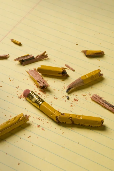 Broken pencil fragments on yellow paper — Stock Photo, Image