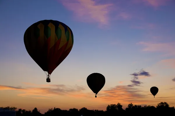 Warme lucht ballonnen drijvende tegen een roodachtig dageraad hemel — Stockfoto