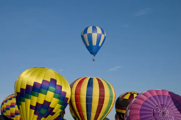 Hot-air balloon ascending over other inflating ones — Stock Photo, Image