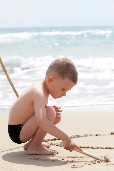 Junge schreibt auf Sand — Stockfoto