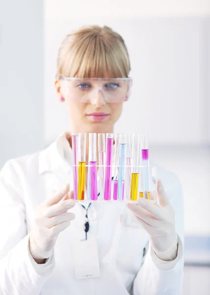 Женщина-исследователь держит пробирку в лаборатории — стоковое фото