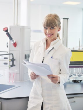 Female researcher holding up a test tube in lab clipart