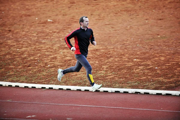 Hombre adulto corriendo en pista de atletismo — Foto de Stock