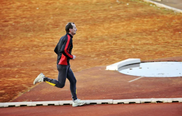 Dospělý muž běží na atletické dráze — Stock fotografie