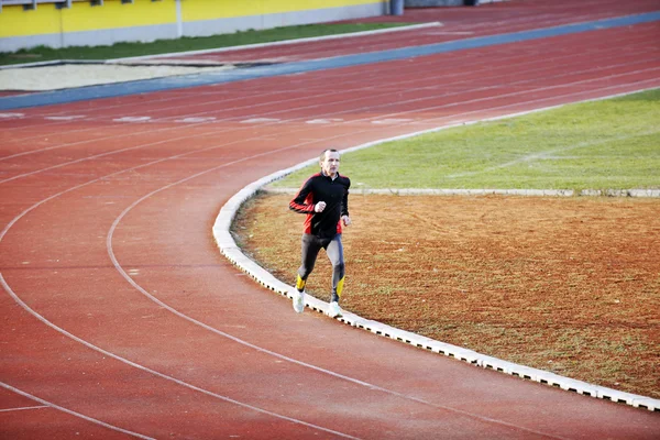 Homem adulto correndo na pista de atletismo — Fotografia de Stock
