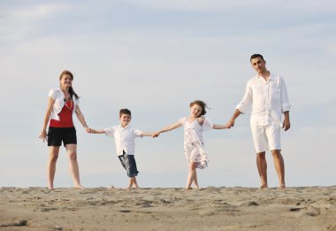 Mutlu genç aile gün batımında sahilde eğleniyor.