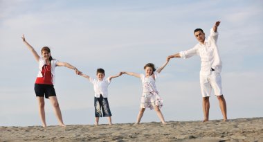 Mutlu genç aile gün batımında sahilde eğleniyor.