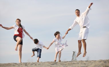 Mutlu genç aile gün batımında sahilde eğleniyor.