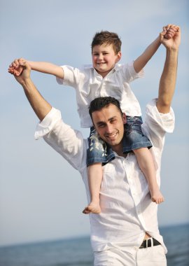 Happy father and son have fun and enjoy time on beach clipart