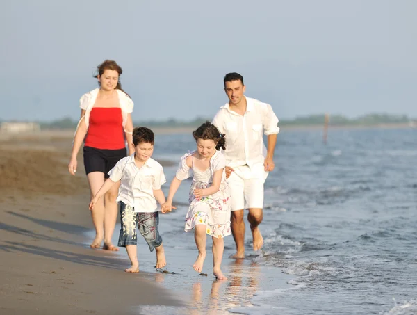 Onnellinen nuori perhe pitää hauskaa rannalla auringonlaskun aikaan — kuvapankkivalokuva