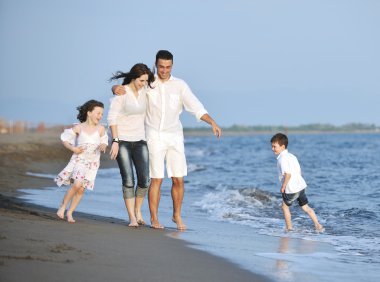 Mutlu genç aile gün batımında sahilde eğleniyor.