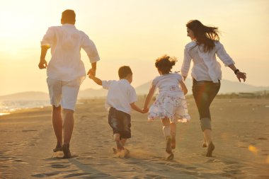 Happy young family have fun on beach at sunset clipart