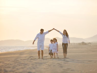 Happy young family have fun on beach at sunset clipart