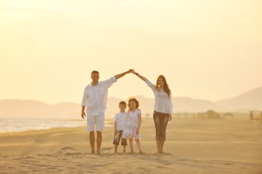 Mutlu genç aile gün batımında sahilde eğleniyor.