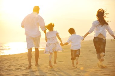 Happy young family have fun on beach at sunset clipart