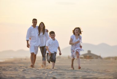 Mutlu genç aile gün batımında sahilde eğleniyor.